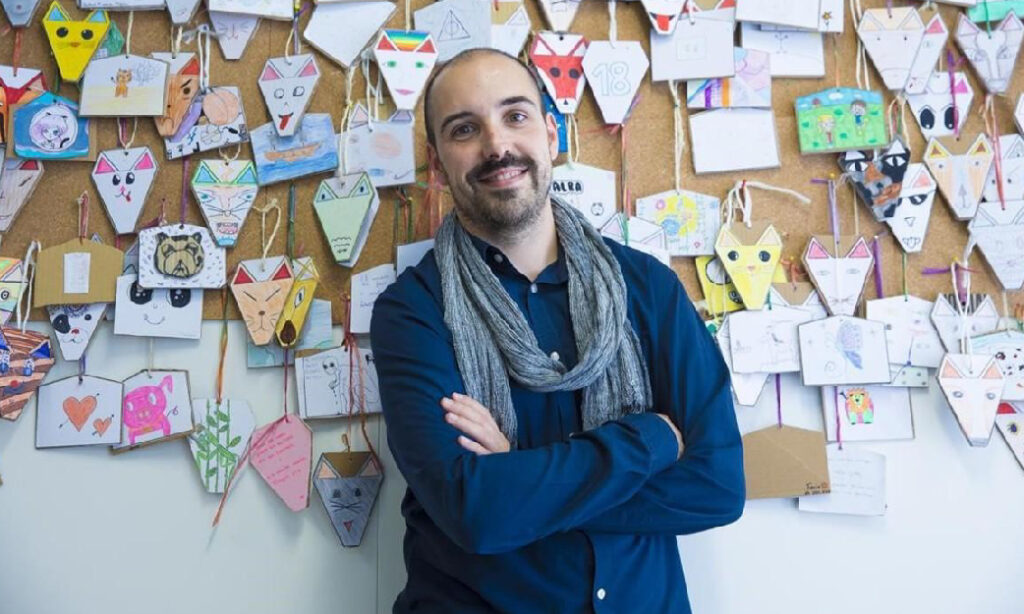 Fotografía de Oriol Julià sobre un fondo con cartas y dibujos de niños y niñas colgando de una pizarra, para la portada del pódcast sobre crecimiento personal como motor del cambio