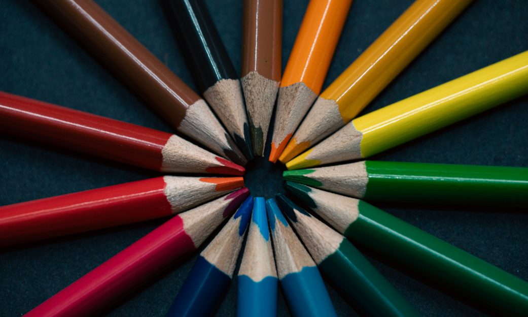 Lápices de diferentes colores apuntando hacia el centro de la fotografía y formando un círculo de colores, fotografía utilizada para la actividad "Pintem les emocions", sobre la reflexión y consciencia de nuestras propias emociones